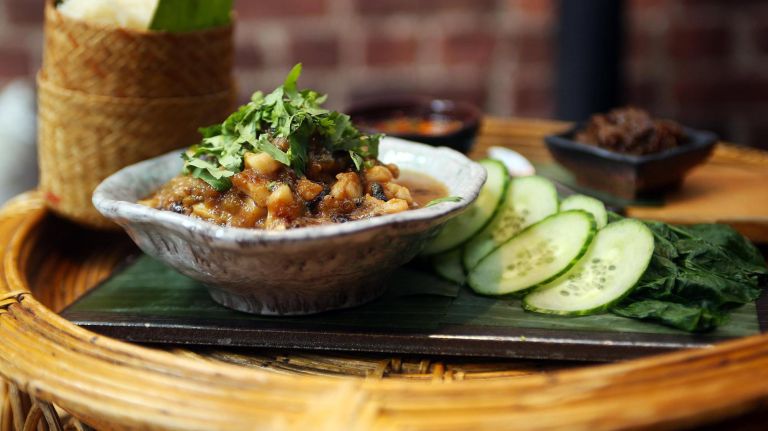 The poached black sea bass at Khe-Yo is made with charred chilies, garlic and shallots, seasoned with padek and fish sauce, and garnished with cilantro.