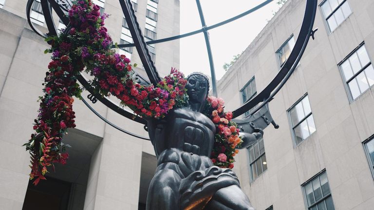 The Atlas statue at Rockefeller Center, draped in a 5,000-flower garland on June 11, created by Lewis Miller Design.