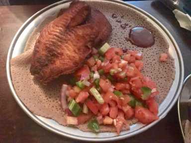 Two big pieces of tilapia over injera bread. (Photo by Gabe Herman)