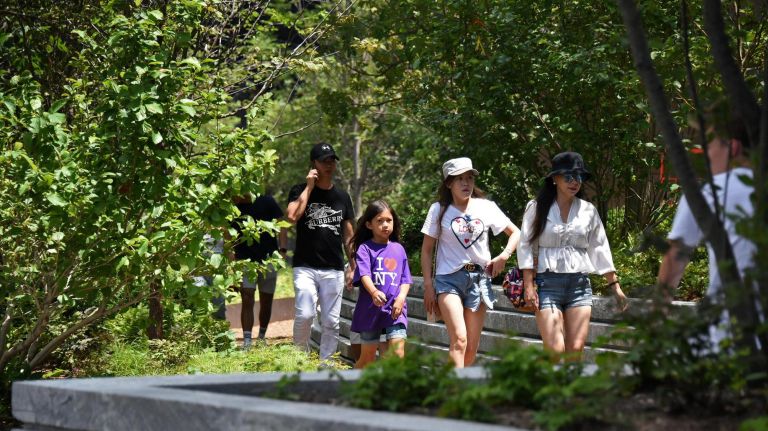 What to do at Hudson Yards: Climb The Vessel, The Shops, the Shed and more 3 People stroll through green space at Hudson Yards in Manhattan.