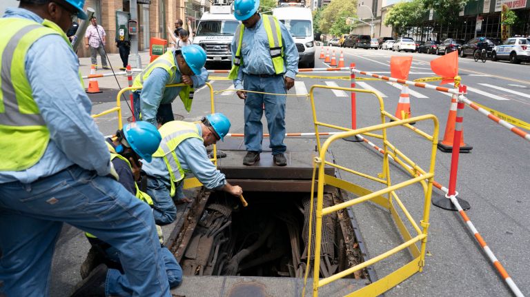 Consolidated Edison workers examine electrical infrastructure under West End Avenue at West 64th Street in Manhattan on Sunday, a day after a widespread power outage hit parts of the borough.