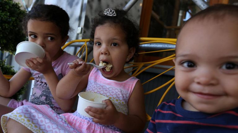 Ila, Zadie and Nico, the owners' children, eat their ice cream outside of Sugar Hill Creamery in Harlem.