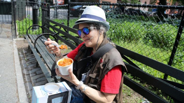 Beth Sopko, a Lower East Side dog walker, sits on a bench while spooning tomato cabbage soup with rice from&nbsp;Chilis on Wheels.