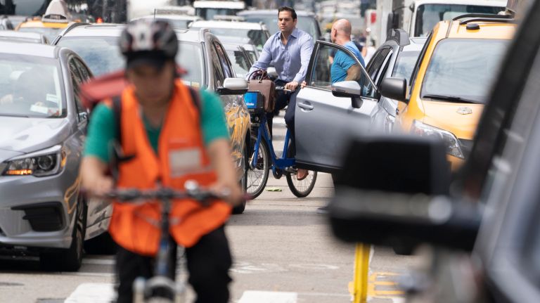 A cyclist navigates around an open car door in the Sixth Avenue bike lane in midtown on July 3.