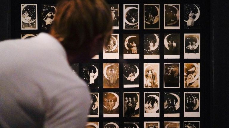 'Apollo's Muse' photo exhibition celebrates 50th anniversary of the moon landing 4 A person looks at Paper Moon Studio Portraits from the 1900s-1930s.