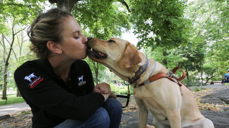 Olivia Poff, a guide dog mobility instructor gets a kiss from " Sunny," a 1.5 year old Yellow Lab that she has been training, June 5, 2019.