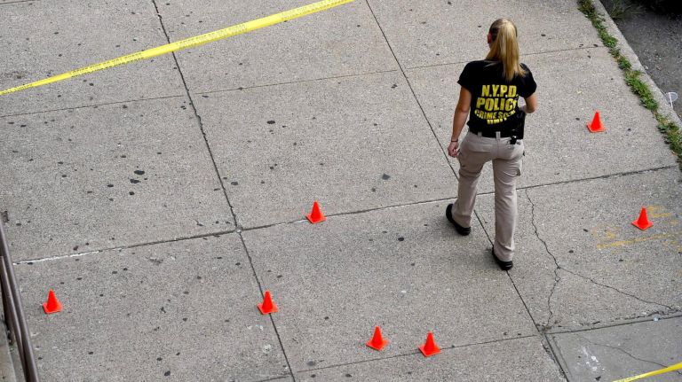 An NYPD investigator walks the scene of the shooting on Howard Avenue.&nbsp;