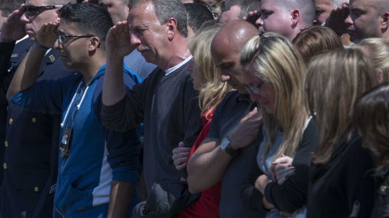 NYPD Officer Brian Moore's father, left, family and friends salute as an ambulance transports Officer Moore from Jamaica Hospital to the Chief Medical Examiner's office in Manhattan on Monday, May 4, 2015.