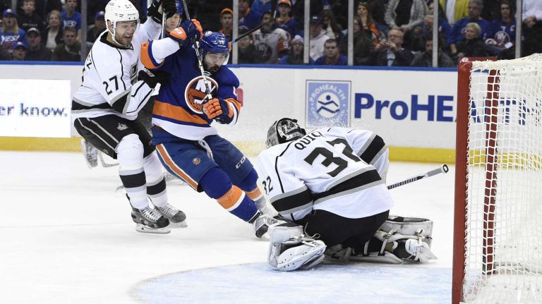 Los Angeles Kings goalie Jonathan Quick makes a save as New York Islanders right wing Cal Clutterbuck reacts in the third period of an NHL hockey game at Nassau Coliseum on Thursday, March 26, 2015. The Kings defeated the Islanders 3-2.