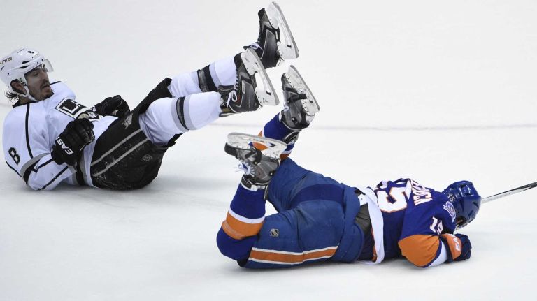 New York Islanders right wing Cal Clutterbuck and Los Angeles Kings defenseman Drew Doughty land on the ice after they collide in the second period of an NHL hockey game at Nassau Coliseum on Thursday, March 26, 2015.
