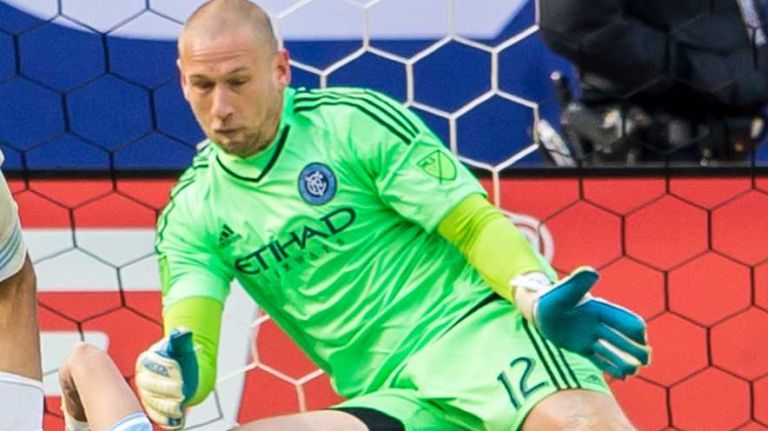 New York City FC goalkeeper Josh Saunders makes a save as New England Revolution forward Juan Agudelo and New York City FC defender Jason Hernandez fall to the ground during a game at Yankee Stadium on Sunday, March 15, 2015.