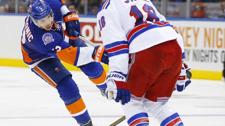 Travis Hamonic of the New York Islanders shoots the puck against Marc Staal of the New York Rangers at Nassau Coliseum on Tuesday, March 10, 2015.