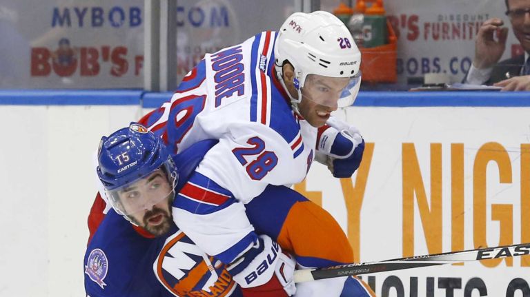 Cal Clutterbuck of the New York Islanders battles for the puck in the second period against Dominic Moore of the New York Rangers at Nassau Coliseum on Tuesday, March 10, 2015.