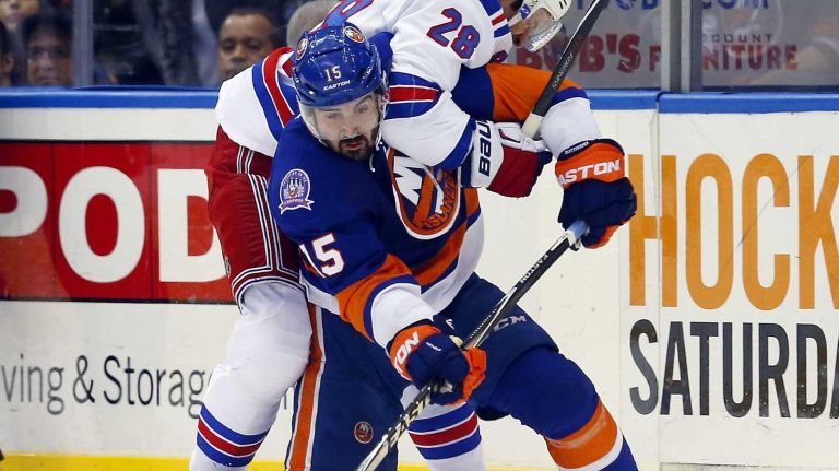 Cal Clutterbuck of the New York Islanders battles for the puck in the second period against Dominic Moore of the New York Rangers at Nassau Coliseum on Tuesday, March 10, 2015.