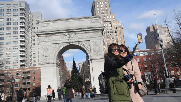 Visitors photograph themselves in front of the arch in Washington Square Park.