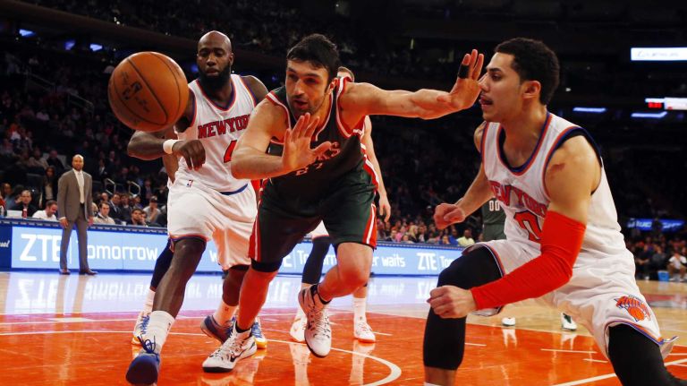 Zaza Pachulia #27 of the Milwaukee Bucks reaches for a loose ball between Quincy Acy #4 and Shane Larkin #0 of the New York Knicks at Madison Square Garden on Sunday, Jan. 4, 2015 in New York City.
