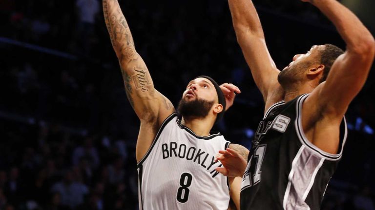 Deron Williams of the Brooklyn Nets lays up a shot against Tim Duncan of the San Antonio Spurs during an NBA game at Barclays Center on Wednesday, Dec. 3, 2014.