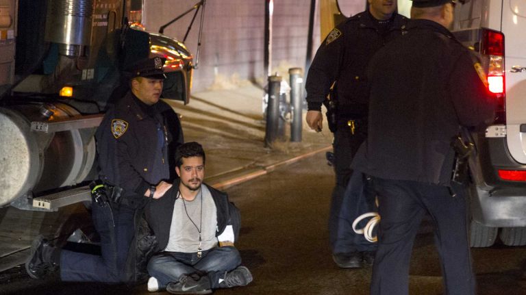 A protester is arrested by NYPD officers at the entrance to the Lincoln Tunnel as groups attempt to block and shut down the tunnel on Tuesday, Nov. 25, 2014, in response to the grand jury decision regarding the fatal shooting of Michael Brown in Ferguson, Mo.