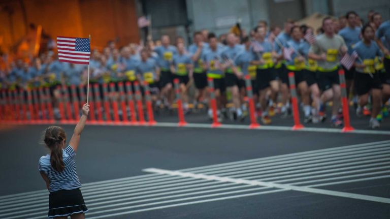 A young bystander waves a flag as runners exit the Hugh L. Carey Tunnel during the 13th Annual Stephen Siller Tunnel To Towers 5K Run & Walk on Sunday, Sept. 28, 2014.