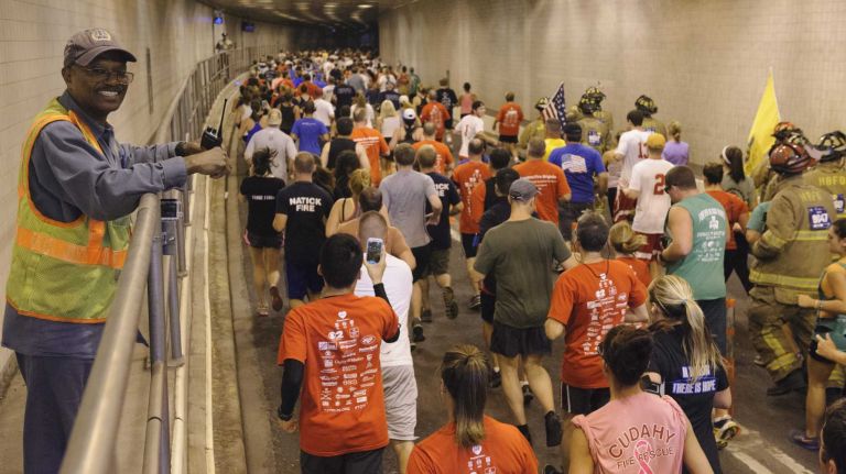 MTA Bridge and Tunnels employee Michael Carrington, left, watches participants in the 2014 Stephen Siller Tunnel To Towers 5K Run & Walk as they enter the Brooklyn entrance to the Hugh L. Carey Tunnel on Sunday, Sept. 28, 2014. 