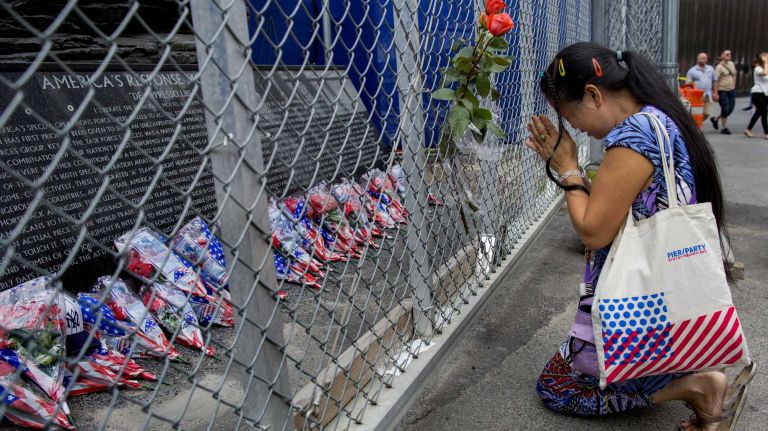 Linn Cai Feng of Brooklyn tearfully says a short prayer after putting flowers of the fence surrounding the American Response Memorial at the PATH station just north of One World Trade Center Thursday, Sept. 11, 2014. Cai Feng said she comes to honor everyone touched by the attacks of 9/11.