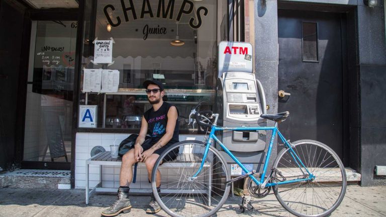 Sato Hilario sits in front of vegan diner Champs Junior in Greenpoint.