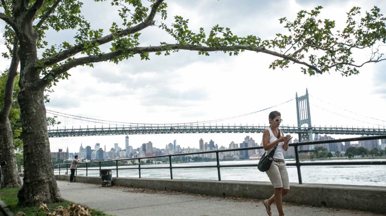 People walk along the East River in Astoria on July 17, 2014.
