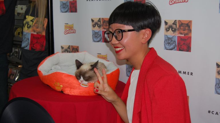 A fan poses with Grumpy Cat at the 