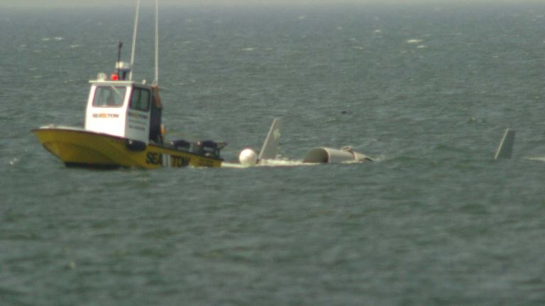 A boat tows the wreckage of a single-engine plane that crashed into the Long Island Sound, killing the pilot, Zubair Khan, about eight miles north of Mattituck Inlet, on July 7, 2014.