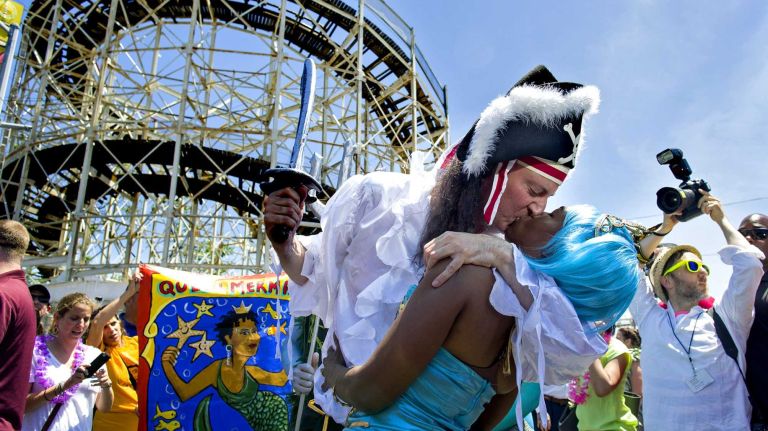 Chirlane McCray and her husband, New York City Mayor Bill de Blasio, kiss near the Cyclone roller coaster as they march in the annual Coney Island Mermaid Parade on Saturday, June 21, 2014.