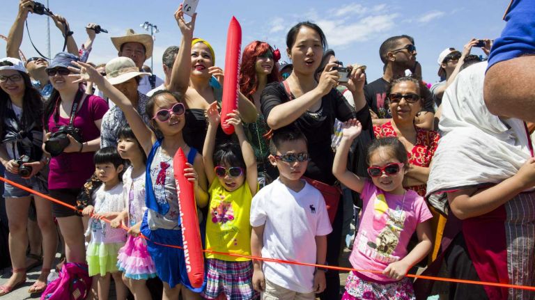 Spectators watch as floats pass by on the boardwalk during the annual Coney Island Mermaid Parade on Saturday, June 21, 2014.