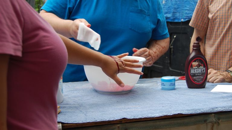 Prop Master Jay Duckworth exhibits how well the blood drips down a person's wrist. 