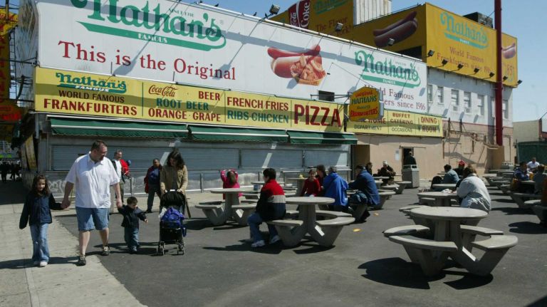 People sit outside Nathan's on Surf Avenue in Coney Island on a warm Sunday on March 28, 2004. 