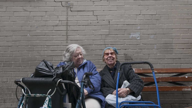 Florence Horn and Eileen Calhoon sit on a bench along Broadway in Kingsbridge.