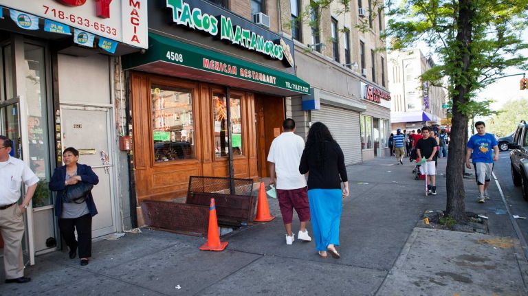 New Yorkers walk along 5th Avenue in front of Tacos Matamoros.