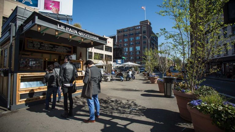 A pedestrian plaza at 14th St. and 9th Ave. with food vendors and benches. 