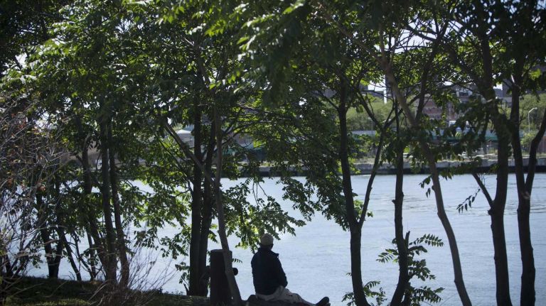 A man sits along the Harlem River in the Harlem River Yards.