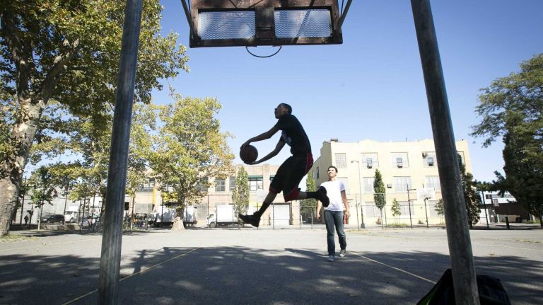Grand Street Campus High School student Ronald Cruise, 14, of East New York, tries to dunk a basketball at Cooper Park as Andy Dortra, 17, of Queens, watches. (Sept. 17, 2013)