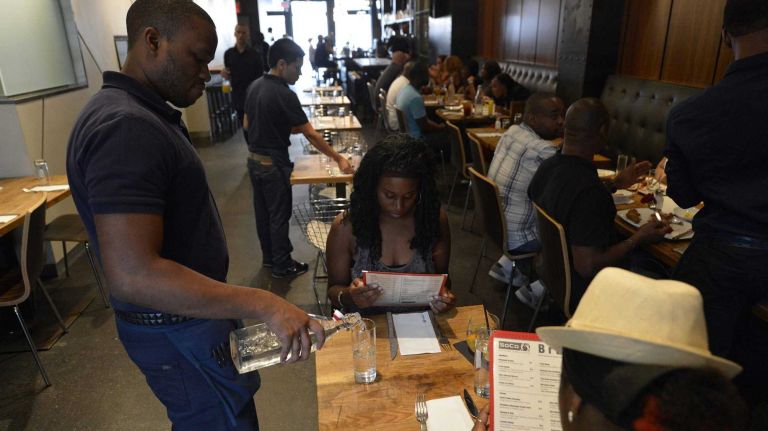 A waiter pours water to guests before their meal at Soco on Myrtle Avenue. (August 10, 2013)