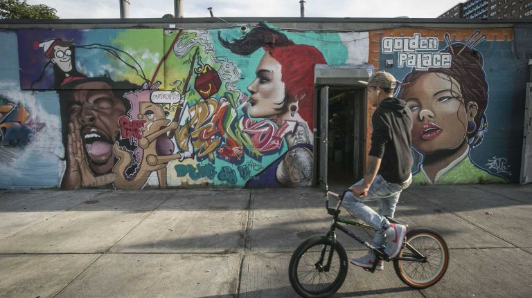A man rides past a mural on Seward Avenue.