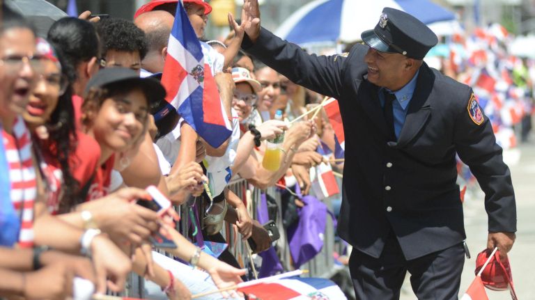 Dominican Day Parade brings color to a cloudy New York City 7 A city firefighter gives high-fives to revelers he passes.