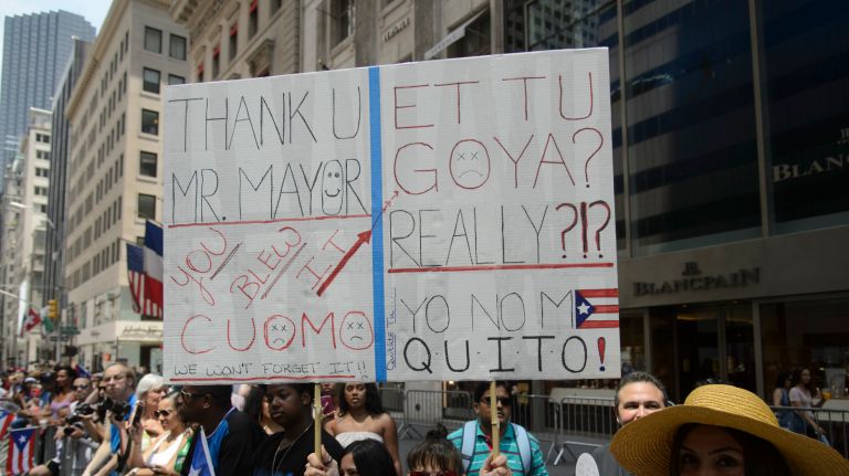 A spectator holds a sign chastising Gov. Andrew Cuomo and the food company Goya for not attending the 60th annual Puerto Rican Day Parade on Sunday, June 11, 2017.