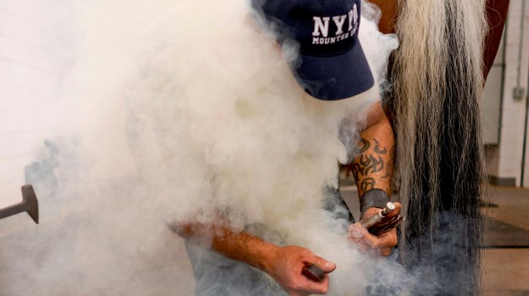 Steam and smoke envelopes Martinez as he works.