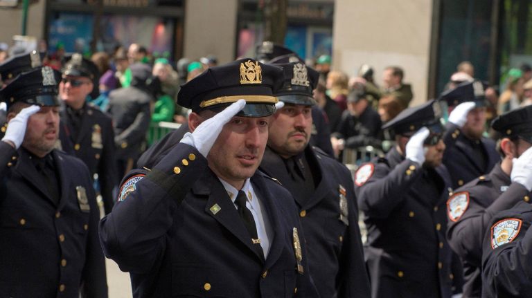 NYPD officers saluted as they marched along Fifth Avenue during the St. Patrick's Day Parade in Manhattan on Saturday.