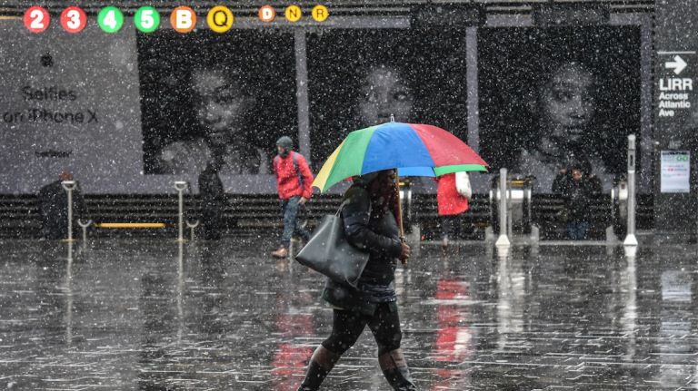 This rainbow-colored umbrella matches the subway sign in the background as a nor'easter bears down on Brooklyn on March 2, 2018.
