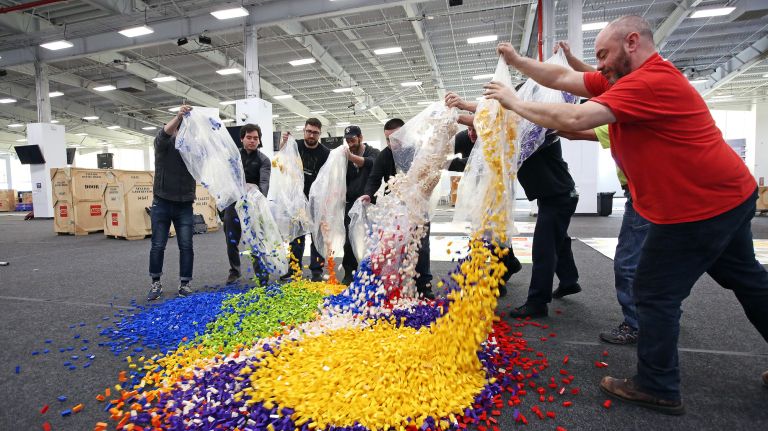 Workers dump thousands of Legos on the floor of Pier 36.