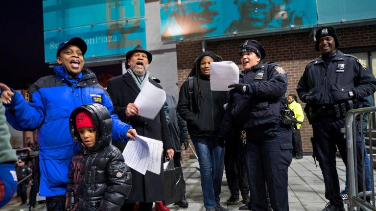NYPD officers in the 79th precinct sing Christmas carols before handing out gifts to children in Bed-Stuy on Dec. 21, 2017.