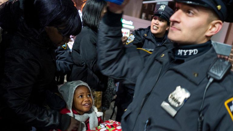 NYPD officers in the 79th precinct hand out gifts to children, as part of the Brooklyn North second annual Sleigh Ride, on Dec. 21, 2017.