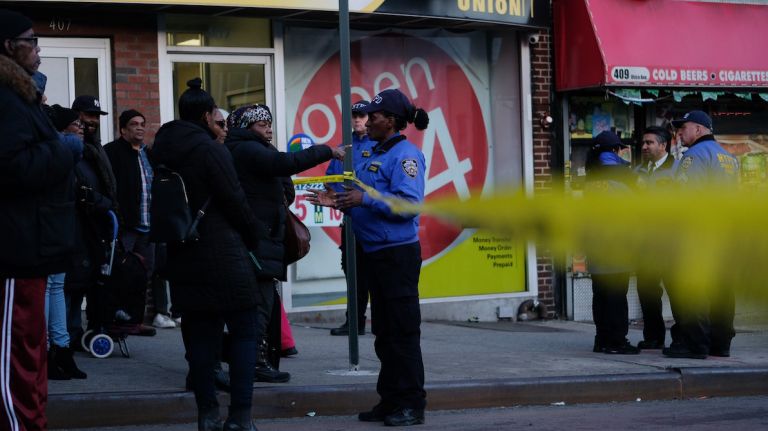 A police officer talks with civilians following a fatal police-involved shooting in Crown Heights on Wednesday.