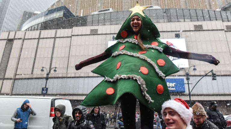 A woman dressed as a Christmas tree stands in front of Madison Square Garden in midtown during SantaCon on Saturday, Dec. 9, 2017.